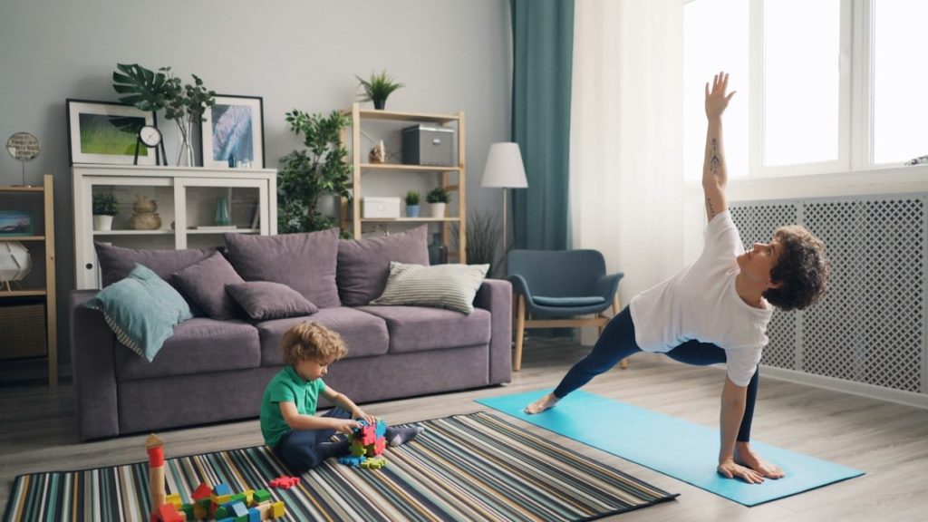 a woman and a child doing yoga in a living room